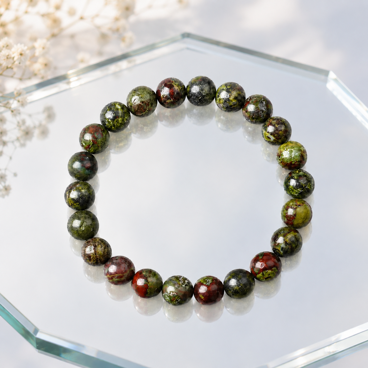Dragon blood stone bracelet on octagonal mirror with white flowers, green red healing crystal stretch bracelet