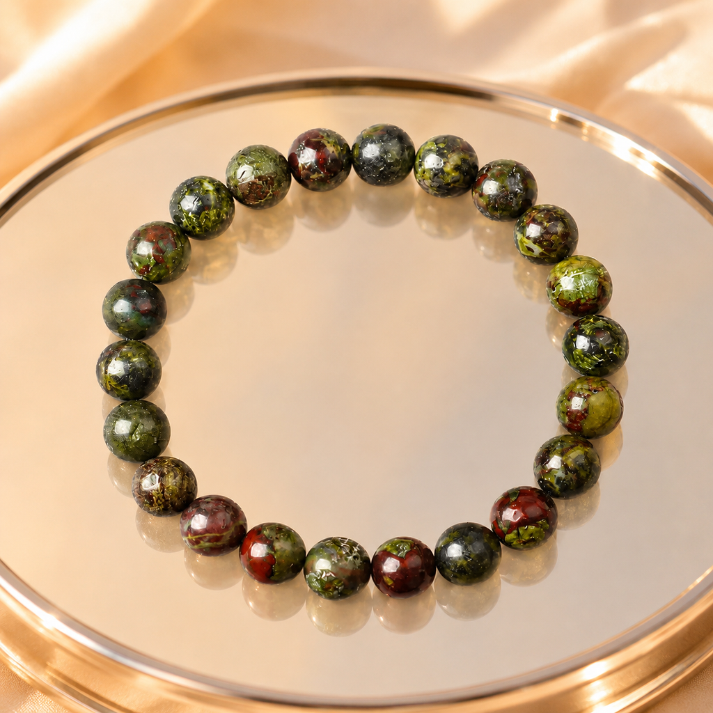 Dragon blood stone bracelet on gold mirror tray with warm satin backdrop, premium green red gemstone jewelry