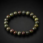 Dragon blood stone bracelet with diagonal spotlight on dark surface, vibrant green red crystal gemstone jewelry