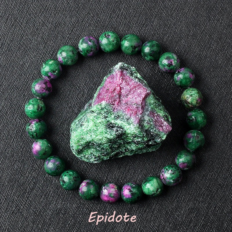 Epidote bracelet with deep green and pink speckled beads surrounding a raw green-pink epidote specimen on dark background