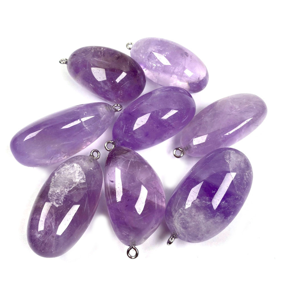 Freeform amethyst pendant assortment with polished purple stone shapes, violet hues from pale to deep, natural-looking inclusions, and silver-color hanging loops arranged on white.