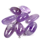 Freeform amethyst pendant assortment with polished purple stone shapes, violet hues from pale to deep, natural-looking inclusions, and silver-color hanging loops arranged on white.