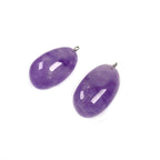 Freeform amethyst pendant pair with smooth polished purple surfaces, varied rounded shapes, visible internal color bands, and tiny silver-color hanging loops on a white background.