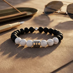 Gemini bracelet with matte onyx, white howlite beads, and silver twins charm styled with sunglasses for smart gifting