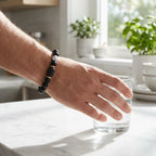 Gemini Zodiac Bracelet on wrist reaching for glass, minimalist black bead astrology jewelry for daily wear and modern lifestyle appeal