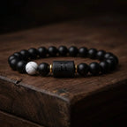 Gemini Zodiac Bracelet on rustic wood surface with black beads and white accent, handcrafted astrology jewelry for unique style expression