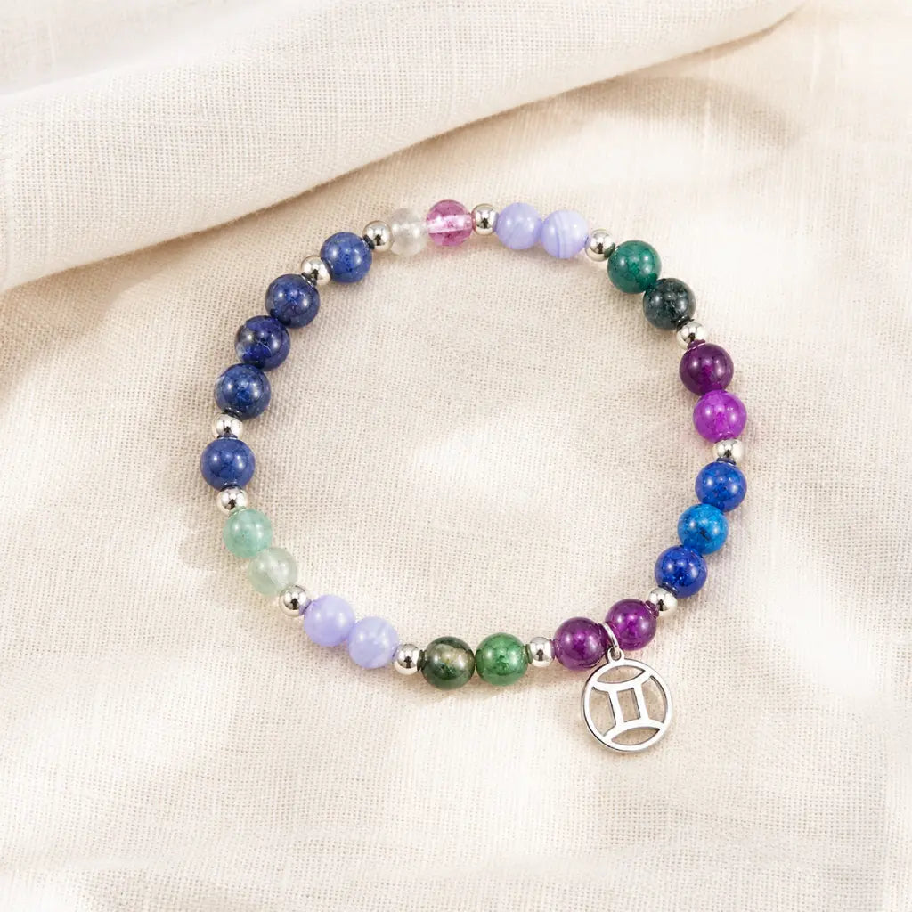 Gemini zodiac crystal beaded bracelet with silver charm on linen. Multicolor healing stones for astrology lovers. Shop unique air sign jewelry gifts.