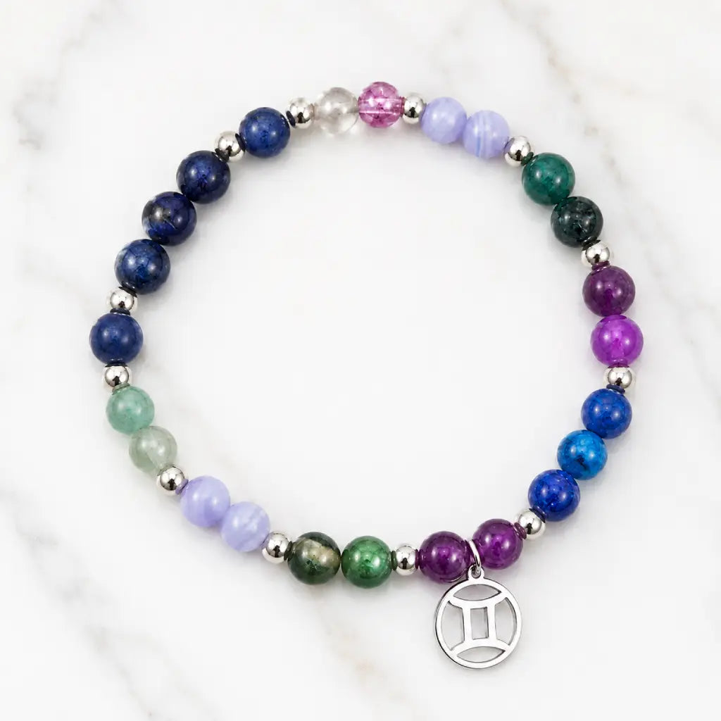 Gemini zodiac beaded bracelet with purple and blue stones on marble. Professional astrology charm jewelry for air signs. Enhance communication and clarity.