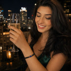 Black onyx lapis lazuli gemstone bead bracelet worn by woman in emerald dress on city rooftop, luxury crystal bracelet celebration night out