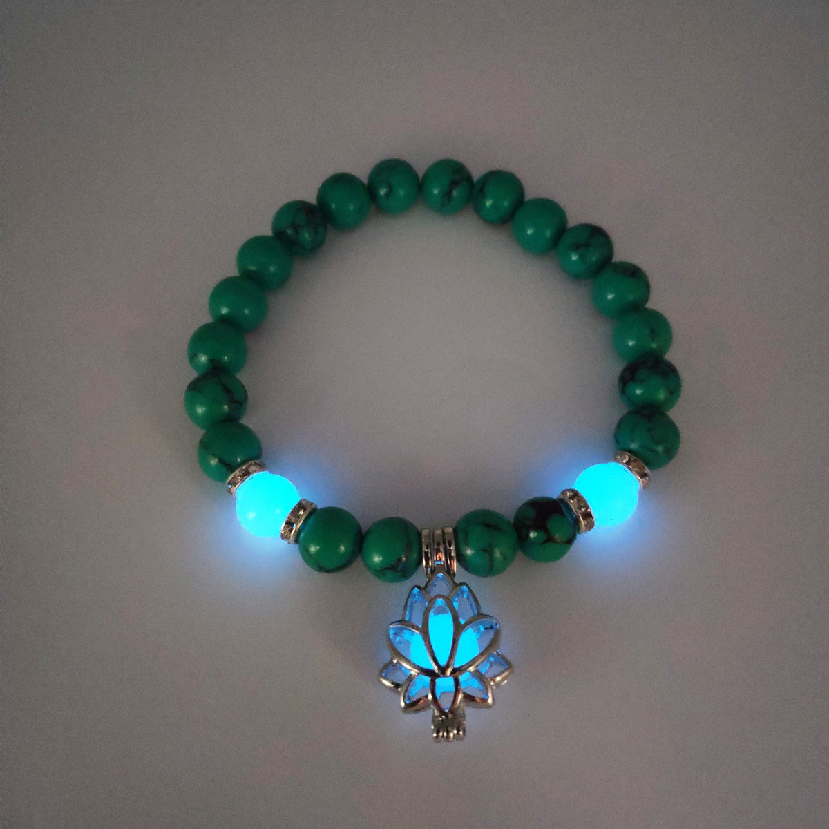 Glow in the dark lotus bracelet green stone beads with a blue glow view, with 8 mm real-stone beads, elastic fit, a silver-color lotus, and light-charged accents for day and night.