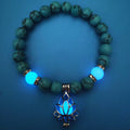 Glow in the dark lotus bracelet blue-green beads with a blue glow view, with 8 mm real-stone beads, elastic fit, a silver-color lotus, and light-charged accents for low-light wear.