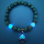 Glow in the dark lotus bracelet blue-green beads with a blue glow view, with 8 mm real-stone beads, elastic fit, a silver-color lotus, and light-charged accents for low-light wear.