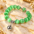 Green catseye bracelet with radiant green beads, silver spacers and ornate charm, styled in golden light for an elegant gift.