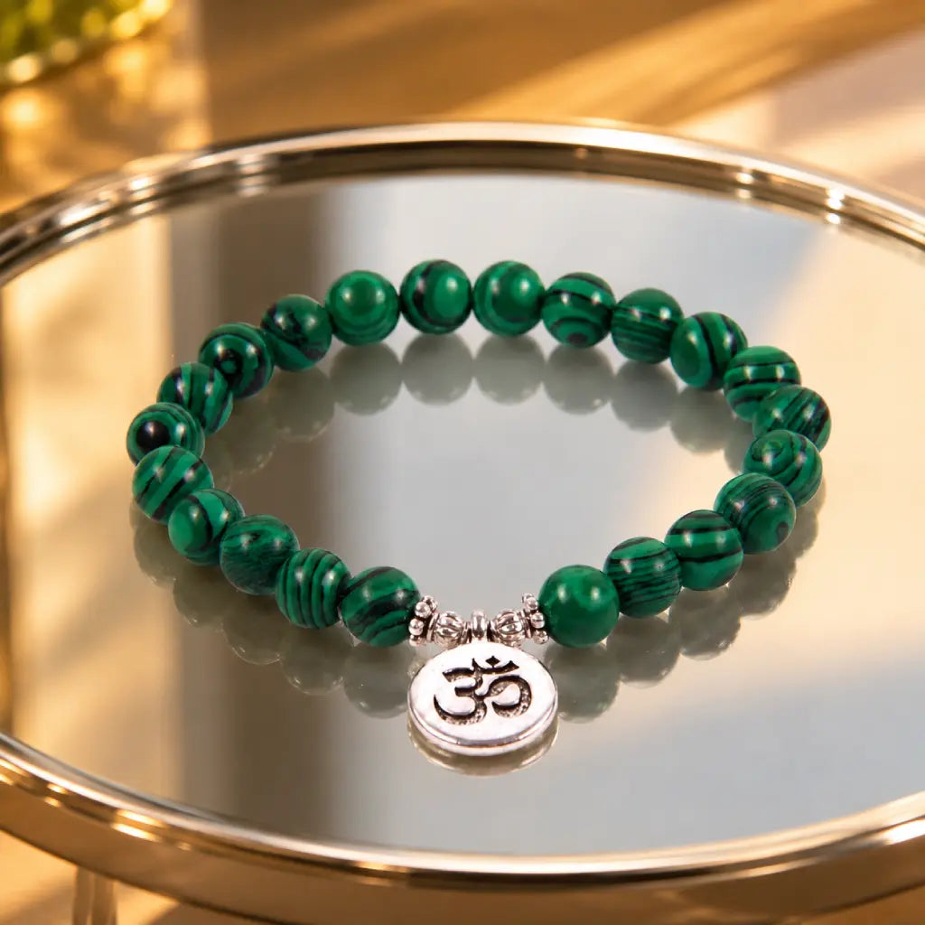 Green tigereye beaded bracelet with natural stone texture and silver Om pendant on glass display