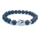 Black Hamsa evil eye bracelet with textured round natural-stone beads, silver-tone alloy spacers and a blue-eye hand centerpiece, displayed at an angle on a clean white background.