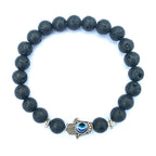 Black Hamsa evil eye bracelet with textured round natural-stone beads, silver-tone alloy spacers and blue-eye hand centerpiece, shown from above on a clean bright white background.
