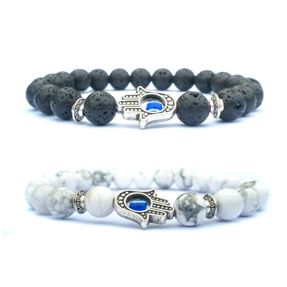 Hamsa evil eye bracelet shown in black and white natural-stone bead options, with silver-tone alloy spacers and blue-eye hand accents on clean, bright white product background set.