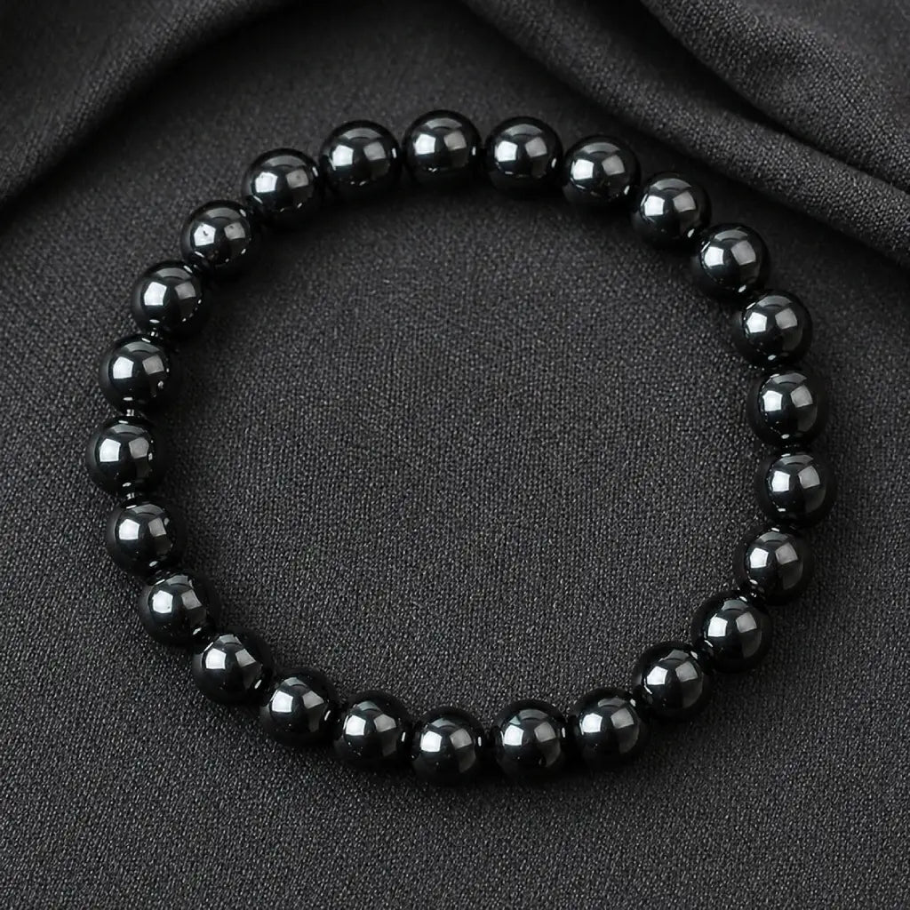 Hematite bracelet glossy round bead jewelry on dark fabric background for grounding energy protection and modern fashion appeal