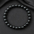 Hematite bracelet glossy round bead jewelry on dark fabric background for grounding energy protection and modern fashion appeal
