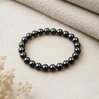 Hematite bracelet smooth polished beads on neutral fabric background symbolizing grounding energy protection and minimalist style