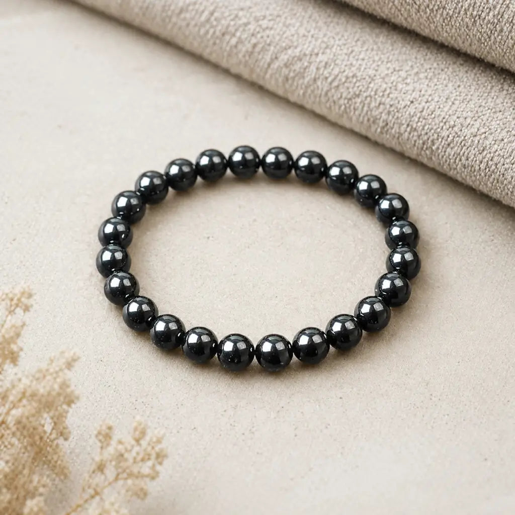 Hematite bracelet smooth polished beads on neutral fabric background symbolizing grounding energy protection and minimalist style