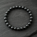 Hematite bracelet black bead jewelry on slate surface highlighting magnetic stone for strength focus energy and modern fashion use