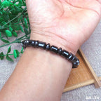 Hematite bracelet with polished black gemstone beads worn on wrist, grounding crystal jewelry for stylish energy balance