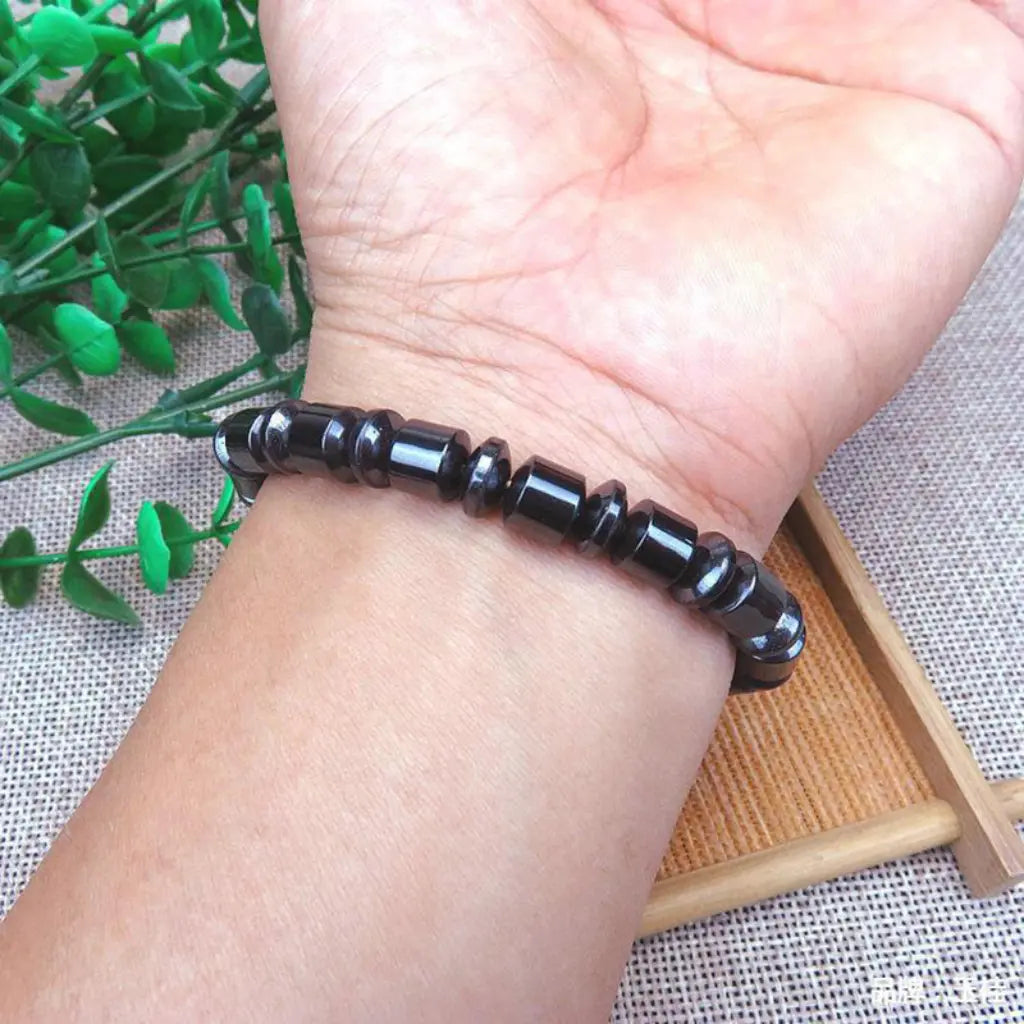 Hematite bracelet with polished black gemstone beads worn on wrist, grounding crystal jewelry for stylish energy balance