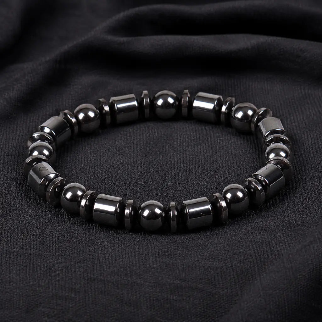 Hematite bracelet with polished black beads and sleek gemstone accents on dark fabric for modern style appeal