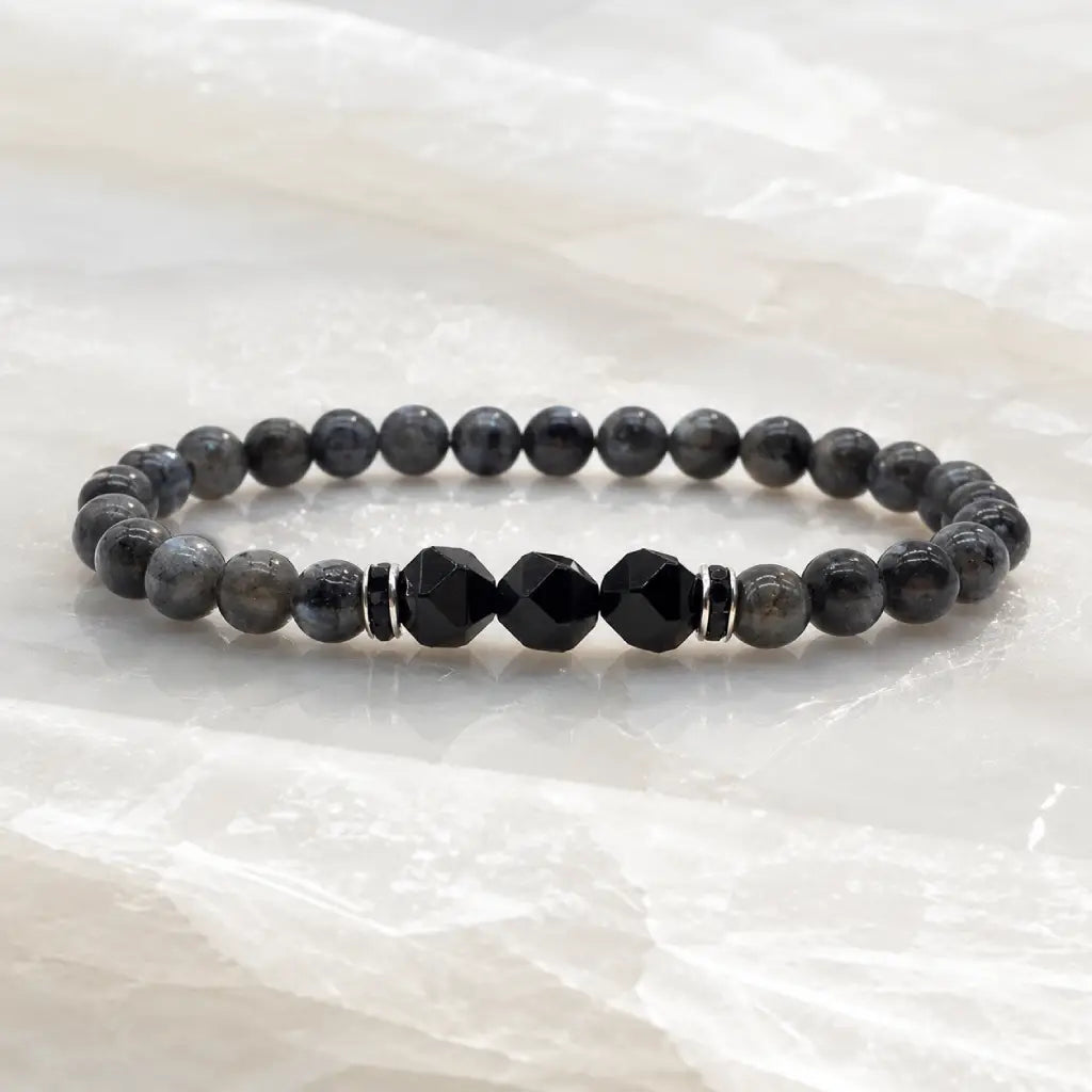 Labradorite and Obsidian bracelet with dark crystal beads on polished marble creating refined minimalist appeal.