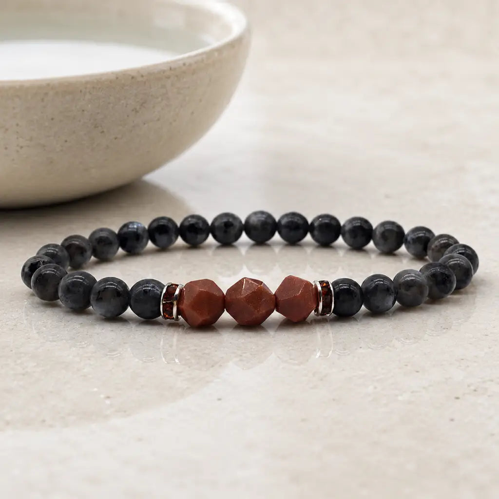Labradorite crystal bracelet displayed beside ceramic bowl with polished healing beads for calm mindful balance