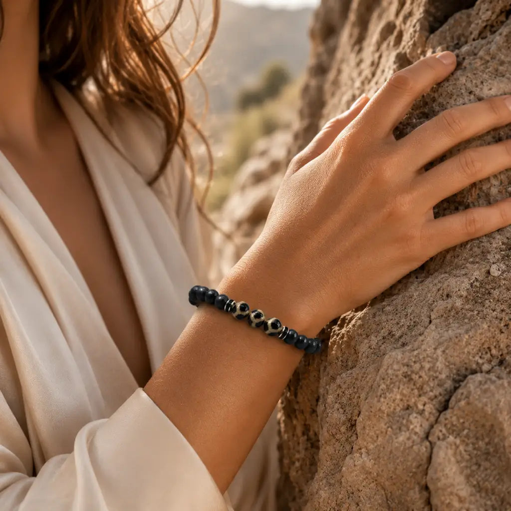 Labradorite dzi bracelet worn near natural rock with black gemstone beads for grounding outdoor wellness style