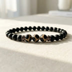 Labradorite dzi bracelet with black beads and glossy Dzi stones displayed on white crystal for calming energy