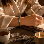 Labradorite dzi bracelet worn while journaling beside tea and candle for mindful spiritual focus and calm