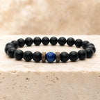 Lapis lazuli and matte black onyx bracelet displayed on warm travertine stone surface, premium natural gemstone bracelet gift for men women