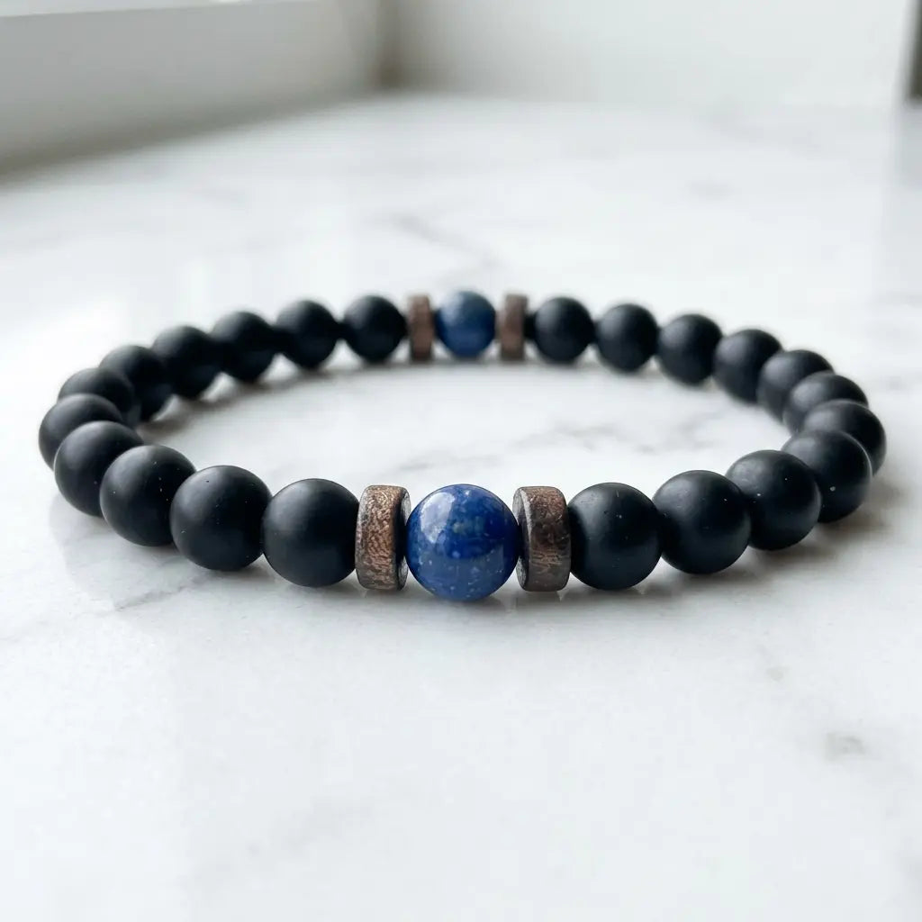 Lapis lazuli center stone black onyx beaded bracelet resting on white marble, minimalist product photography natural crystal healing bracelet