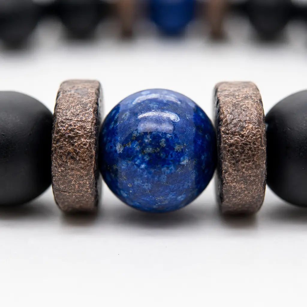 Lapis Lazuli onyx bracelet macro showing a polished blue lapis lazuli bead framed by textured spacers and matte black onyx beads.