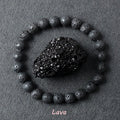 Lava stone bracelet with rough porous dark black volcanic beads surrounding a raw lava rock specimen on dark grey background