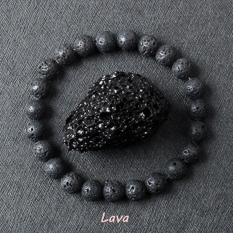Lava stone bracelet with rough porous dark black volcanic beads surrounding a raw lava rock specimen on dark grey background