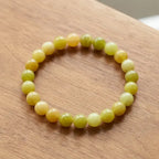 Lemon jade bracelet on wooden surface with glossy yellow beads, natural stone jewelry for warm organic styling appeal
