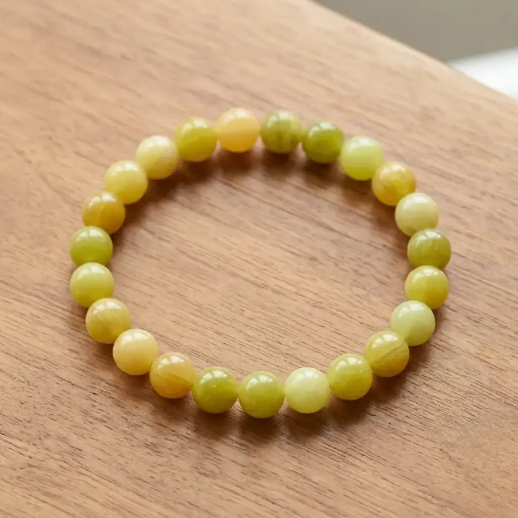 Lemon jade bracelet on wooden surface with glossy yellow beads, natural stone jewelry for warm organic styling appeal
