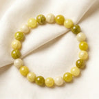 Lemon jade bracelet arranged on soft fabric with glossy green beads, natural gemstone jewelry for calm styling
