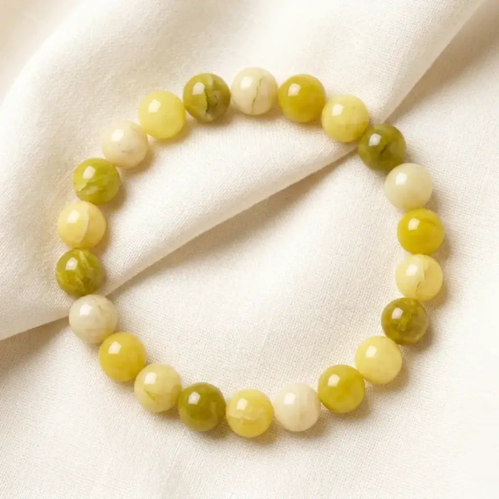 Lemon jade bracelet arranged on soft fabric with glossy green beads, natural gemstone jewelry for calm styling
