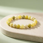 Lemon jade bracelet displayed on marble surface with smooth yellow beads, minimalist gemstone accessory look

