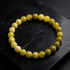 Lemon jade bracelet on dark marble surface with glossy beads, premium gemstone jewelry for bold luxury presentation
