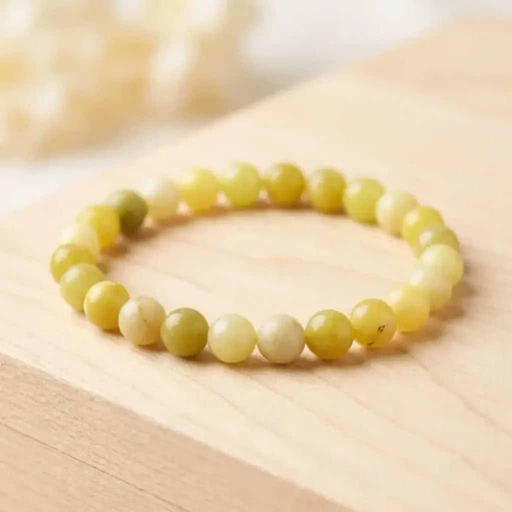 Lemon jade bracelet on light wood surface with smooth yellow beads, natural gemstone jewelry for clean minimal display
