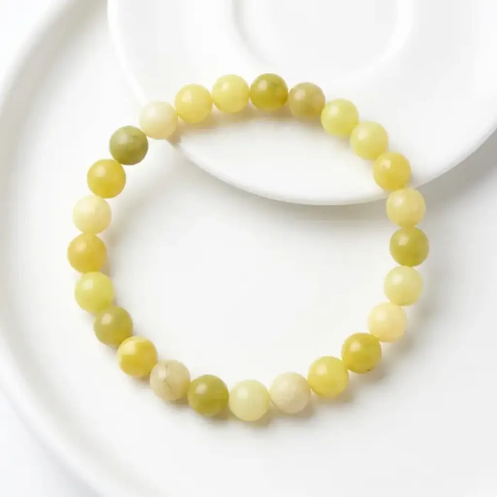 Lemon jade bracelet arranged on white ceramic plate with smooth beads, minimalist gemstone jewelry for modern look
