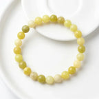 Lemon jade bracelet arranged on white ceramic plate with smooth beads, minimalist gemstone jewelry for modern look
