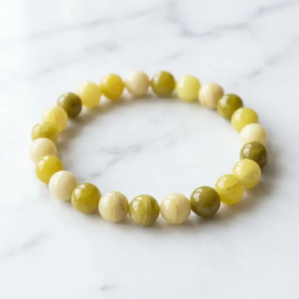 Lemon jade bracelet displayed on marble surface with smooth yellow beads, minimalist gemstone accessory look
