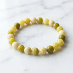 Lemon jade bracelet displayed on marble surface with smooth yellow beads, minimalist gemstone accessory look
